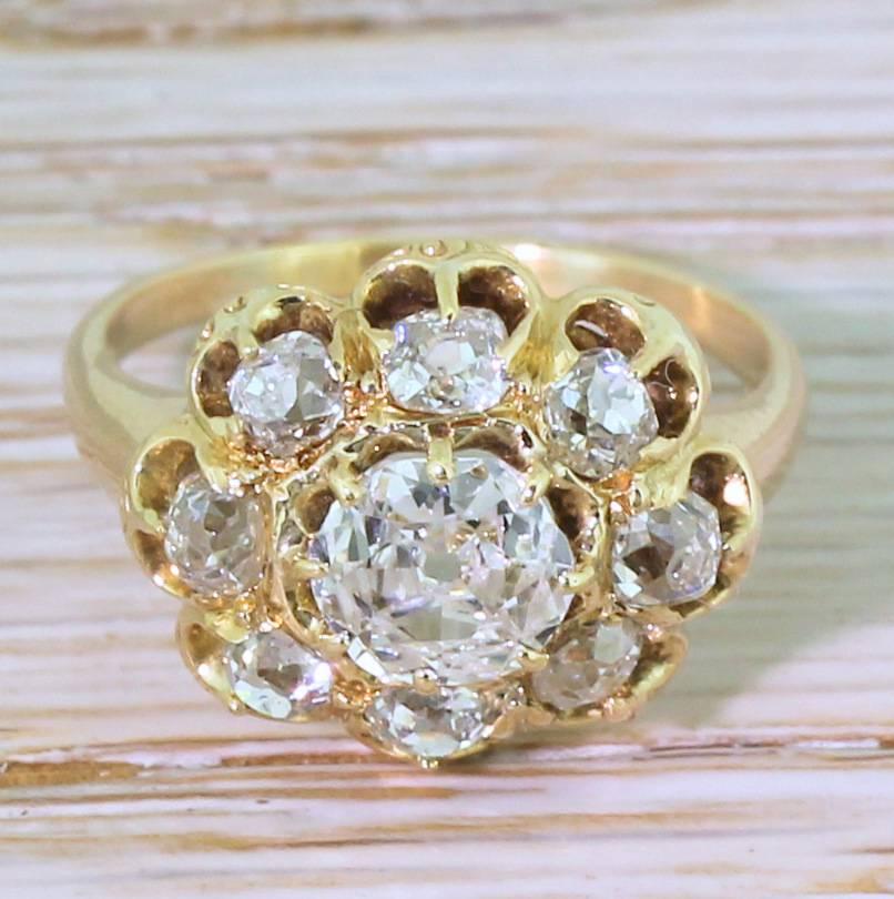An impressive and unique Victorian diamond cluster ring. An old mine cut diamond – white, bright and incredibly internally clean – sits in the centre of eight cushion shaped old cut diamonds. The shape of the cluster is guided by the slight oval