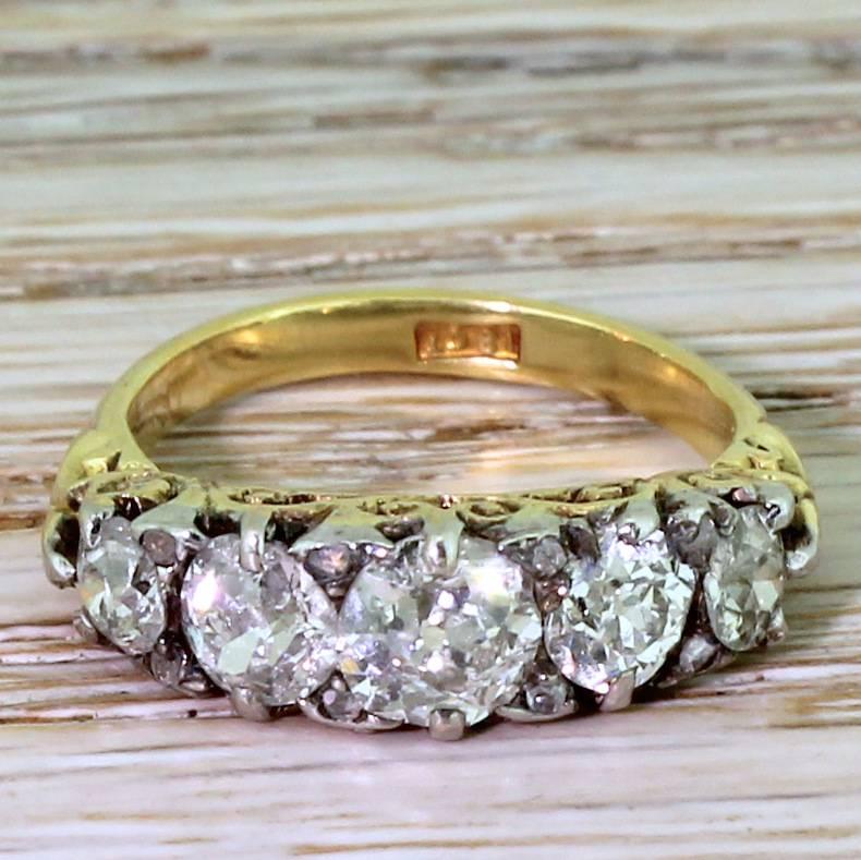A large and impressive carved half hoop five stone diamond ring. The old cut stones are all of a similar high white colour and clarity, with plenty of fire and brilliance. Pairs of small rose cut diamonds are nestled between the larger stones, with