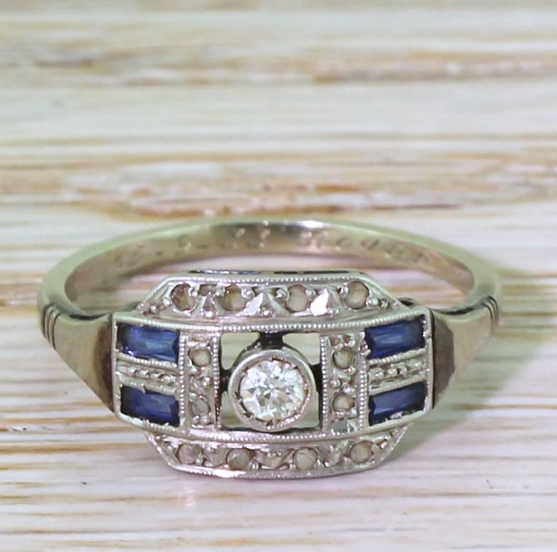 A seriously lovely French Art Deco sapphire and diamond ring. The old mine cut in the centre is rubover and milgrain set in platinum, and floats within a geometric lateral cluster. Adorned with ten small rose cuts and two pairs of baguette cut blue