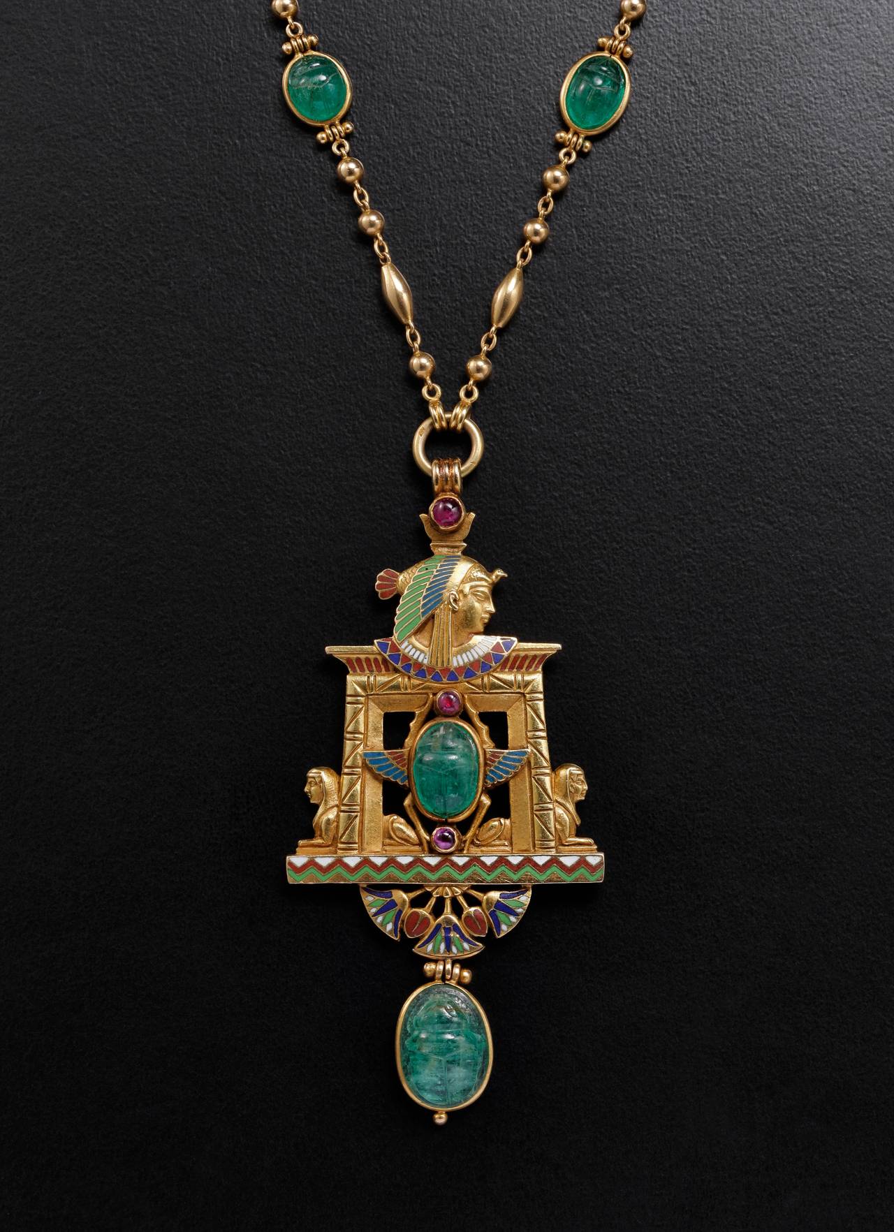 JULES WIESE (1818-1890)

Pendant « Egypt »

Yellow gold, enamel, emeralds, pearls

Paris, circa 1875

UNIQUE PIECE

Inspiration of excavations in Egypt by Mariette Bey 
and the construction of the Suez Canal

The goldsmith and jeweller,