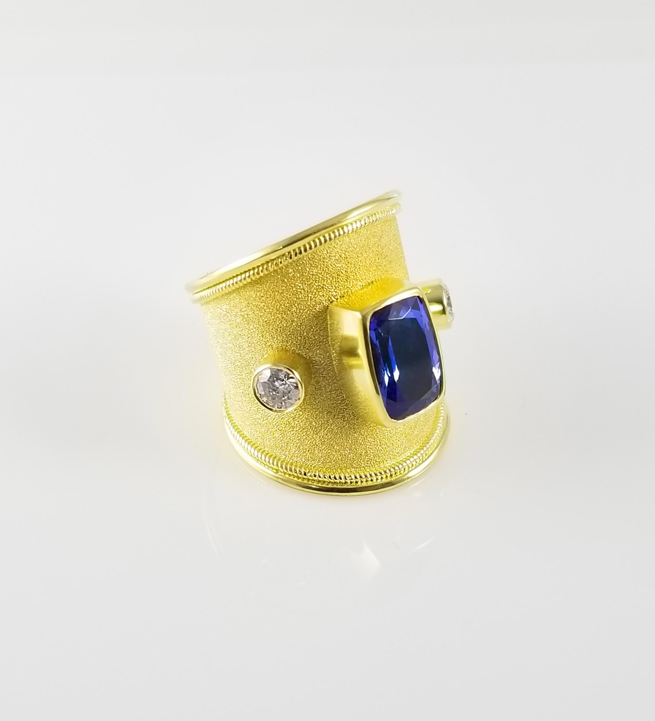 S.Georgios designer 18 Karat Solid Yellow Gold Ring all handmade with a Byzantine Granulation Workmanship and a unique velvet background. The stunning ring has 1 center Cushion Cut Tanzanite total weight of 3,67 Carats and 2 Brilliant cuts of White