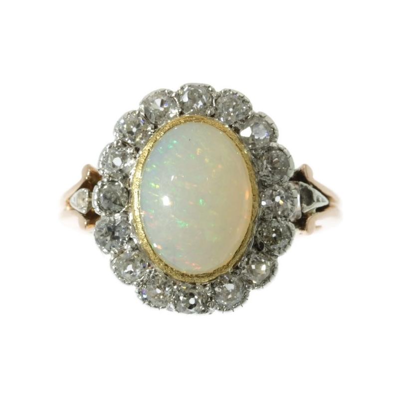 With its central cabochon opal of 3.20 carat, this 18K red gold and silver Victorian ring from 1880 could be your personal wishing well full of red and green shimmers. 16 surrounding old brilliant cut diamonds are encrusted in a bezel setting to