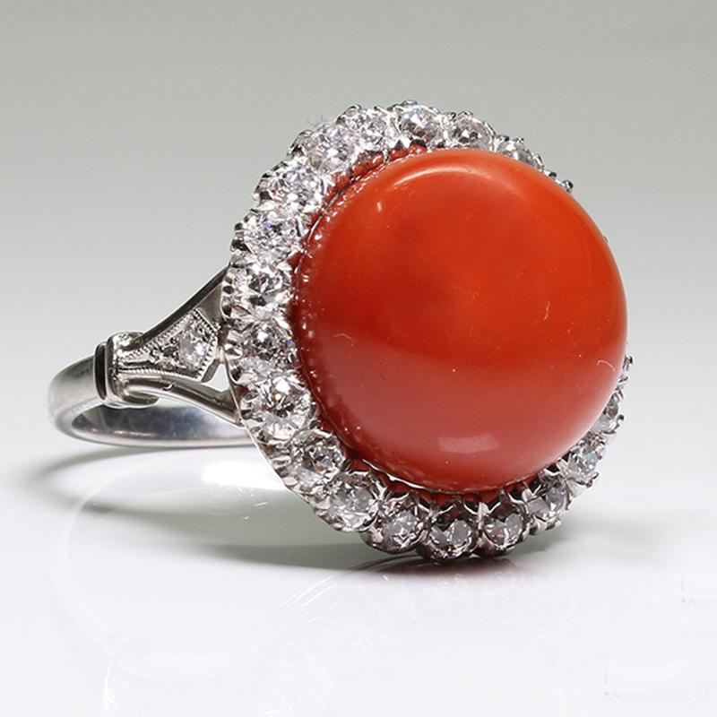 Composition: Platinum
Stones:
•	24 Old mine cut diamonds of G-VS2 quality that weigh 1.40ctw.
•	1 natural cabochon cut intense red color coral that measures 14mm.
Ring size: 8 ¼      
Ring face:  19mm by 19mm 
Rise above finger: 13mm.
Total weight: 