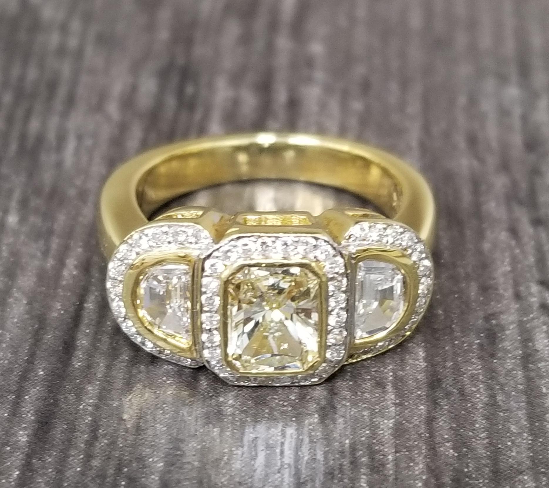 18k yellow gold diamond halo ring containing 1 emerald cut diamond; color 