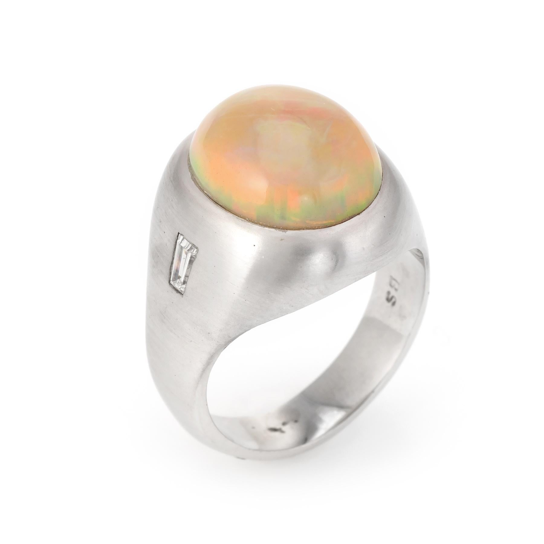 Finely detailed vintage Men's opal & diamond ring (circa 1960s to 1970s), crafted in 14 karat white gold. 

Centrally mounted cabochon cut natural opal measures 15mm x 13mm (estimated at 15 carats), accented with two estimated 0.05 carat baguette