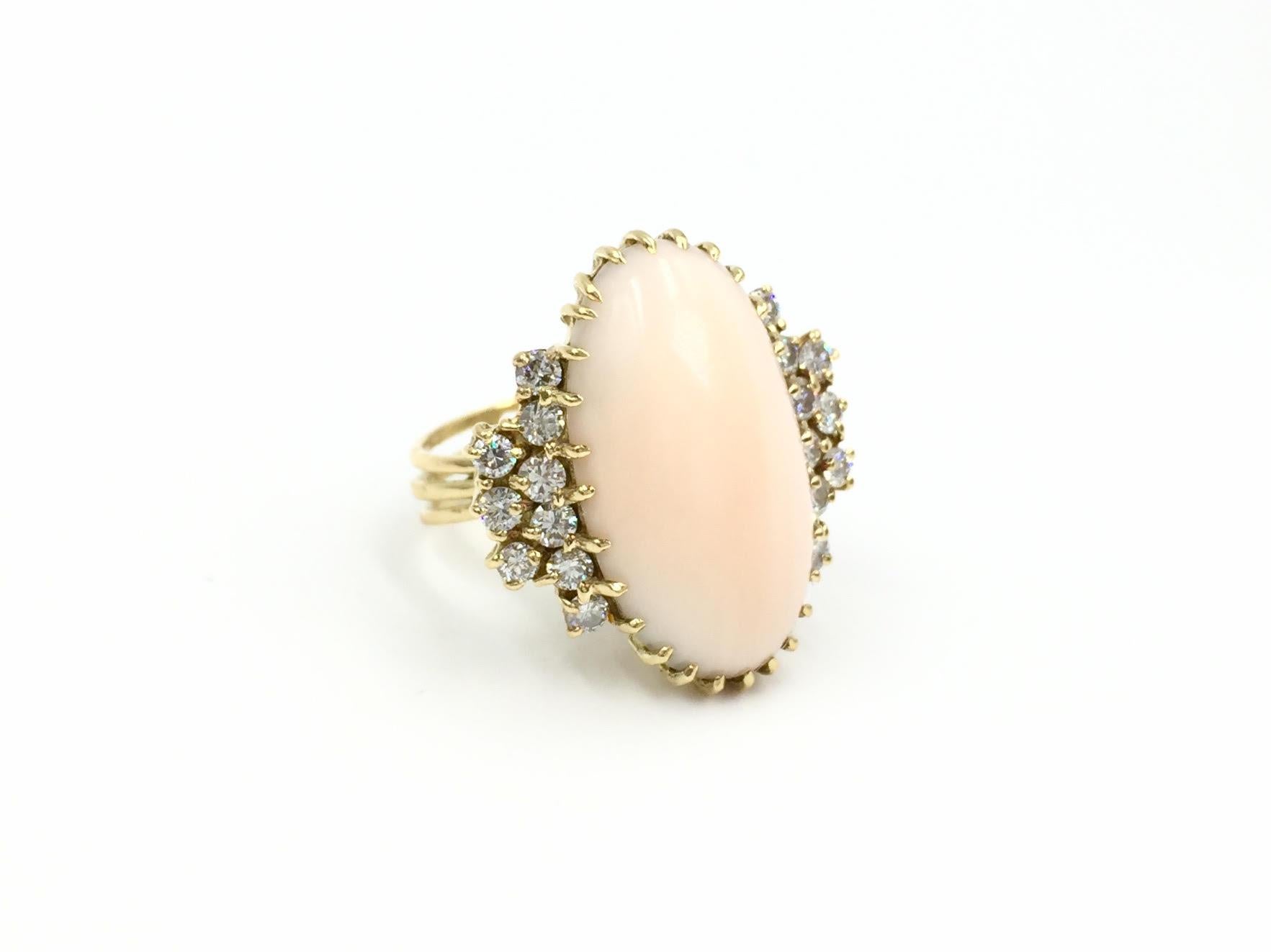Circa 1960's. This beautiful 18 karat yellow gold vintage oval 'angel skin' (pale pink) coral ring features approximately .50 carat of round brilliant diamonds. Diamonds are approximately G color, SI1 clarity. Shank is split in three rows with a