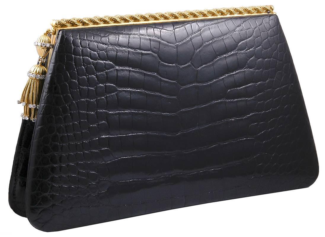 A fine 1950's black alligator clutch with two rows of gold in a twisted rope motif, The clasp featuring two drop-shaped fluted gold bead accented with bands of brilliant-cut diamonds, and suspending multi-strand gold fringe with diamond finishes.