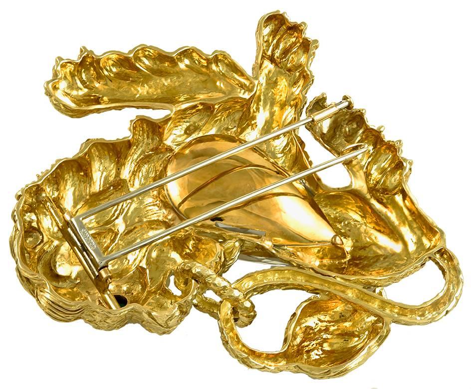 DAVID WEBB Kingdom Lion Rock Crystal Emerald Brooch in 18k Yellow Gold.

A heavily sculpted brooch by David Webb attributed to the Kingdom Collection. Gorgeous engraved trestles of textured gold surround a pear-shaped rose-cut rock crystal in the