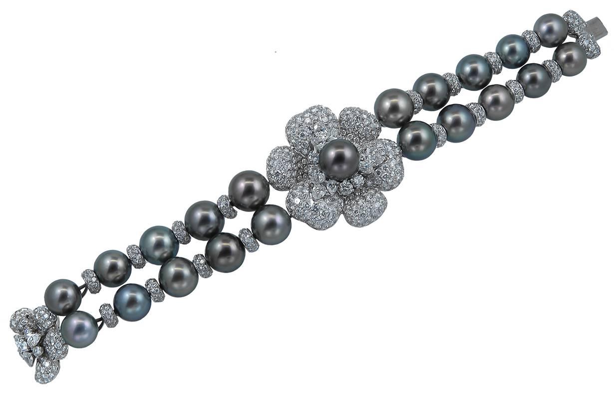 A rare diamond and grey pearl Asprey suite comprising of a two row pearl necklace designed with a diamond flower centre and featuring a detachable hanging pearl pendant, a similarly designed diamond & pearl bracelet, and a pair of hanging pendant