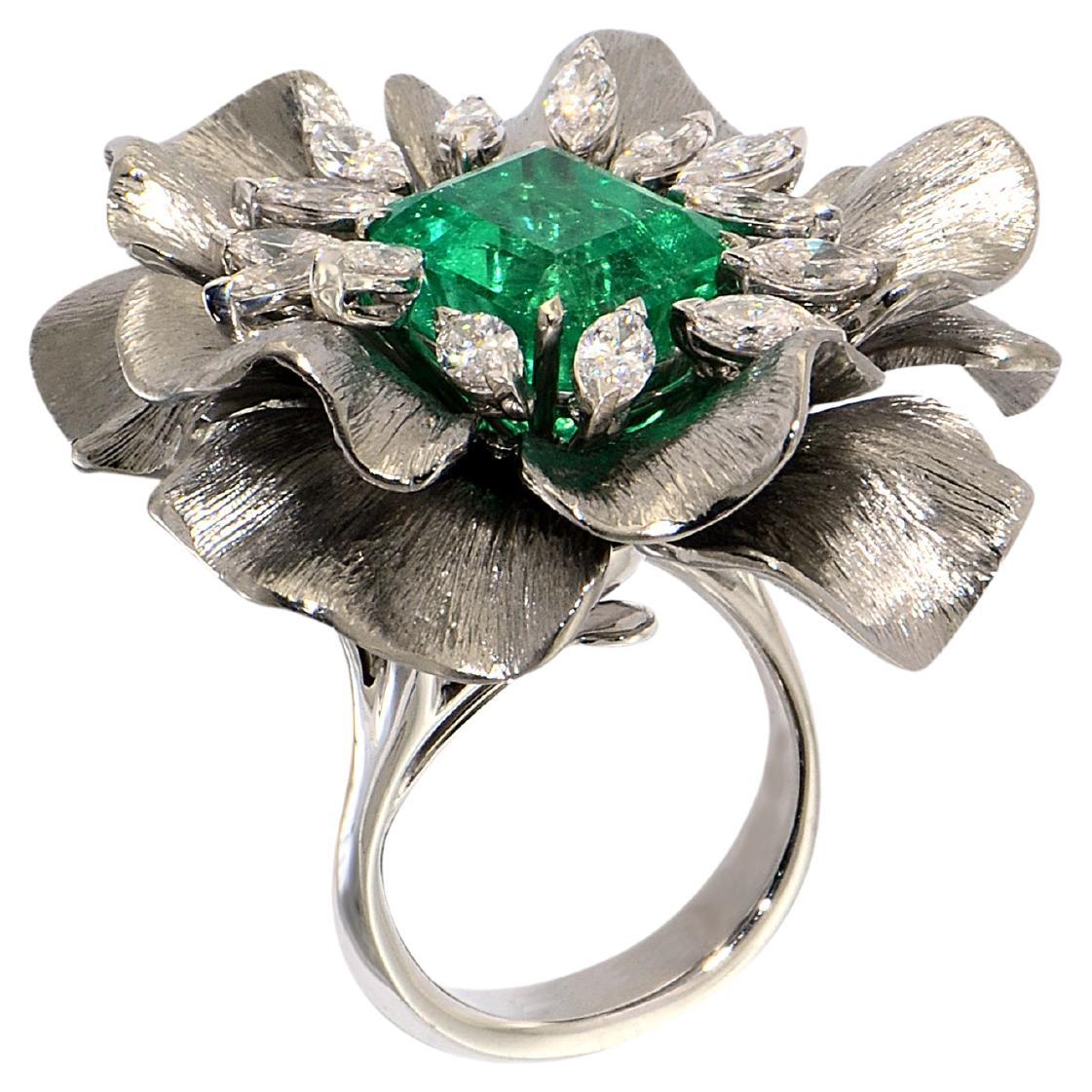 The very special, unique, Happy Flower ring is centering an impressive certificated emerald of 6.07 carats. Decorated by 14 navette cut diamonds of best quality.
Petals are handmade in natural light titanium, burin engraved designing an enchanting
