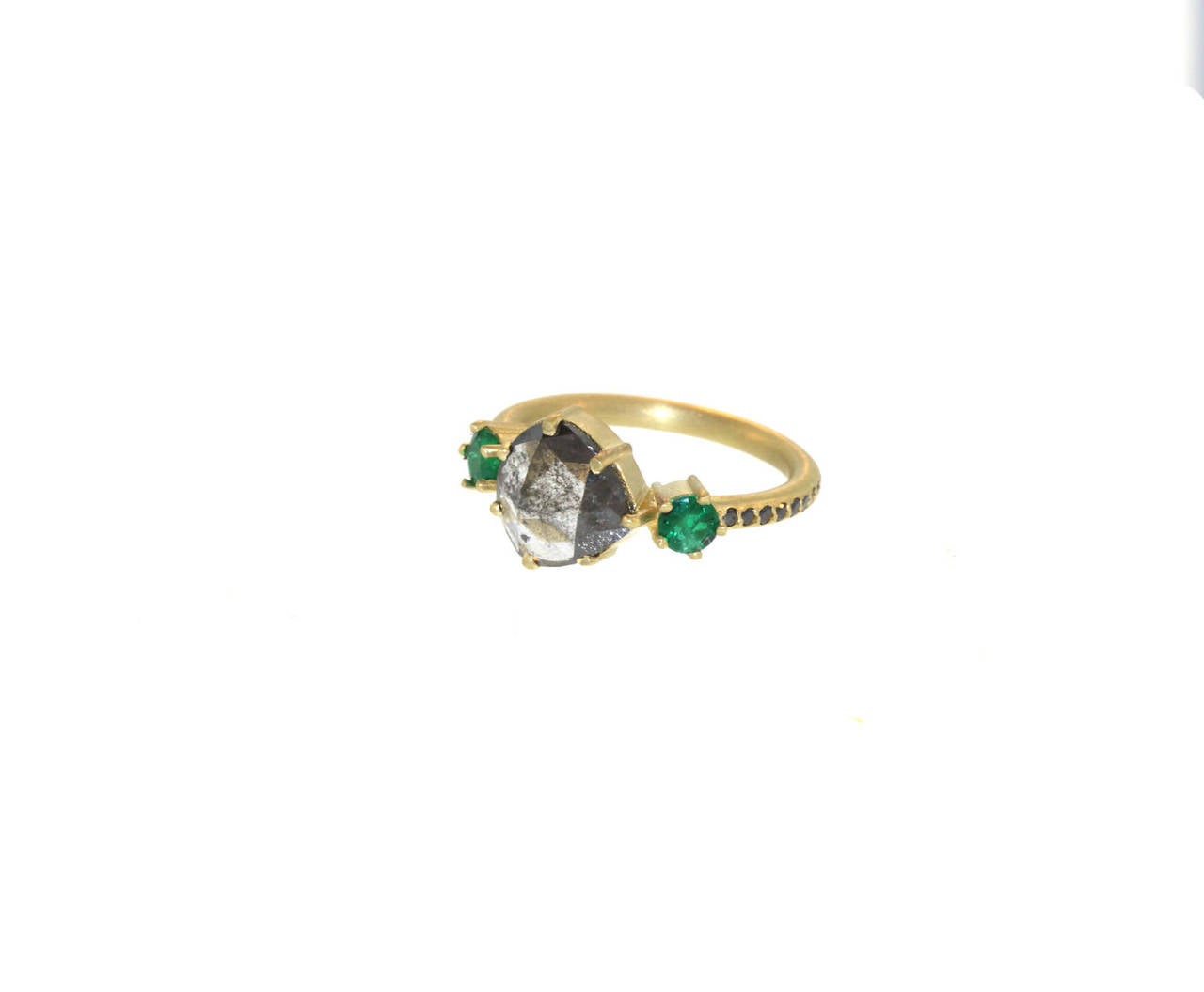 This ring is perfect for someone who is looking for a nontraditional ring. The focal point its beautiful 1.67 carat rose cut opaque diamond, set in between two .37 carat color rich emeralds. The center opaque diamond and emeralds are prong set in