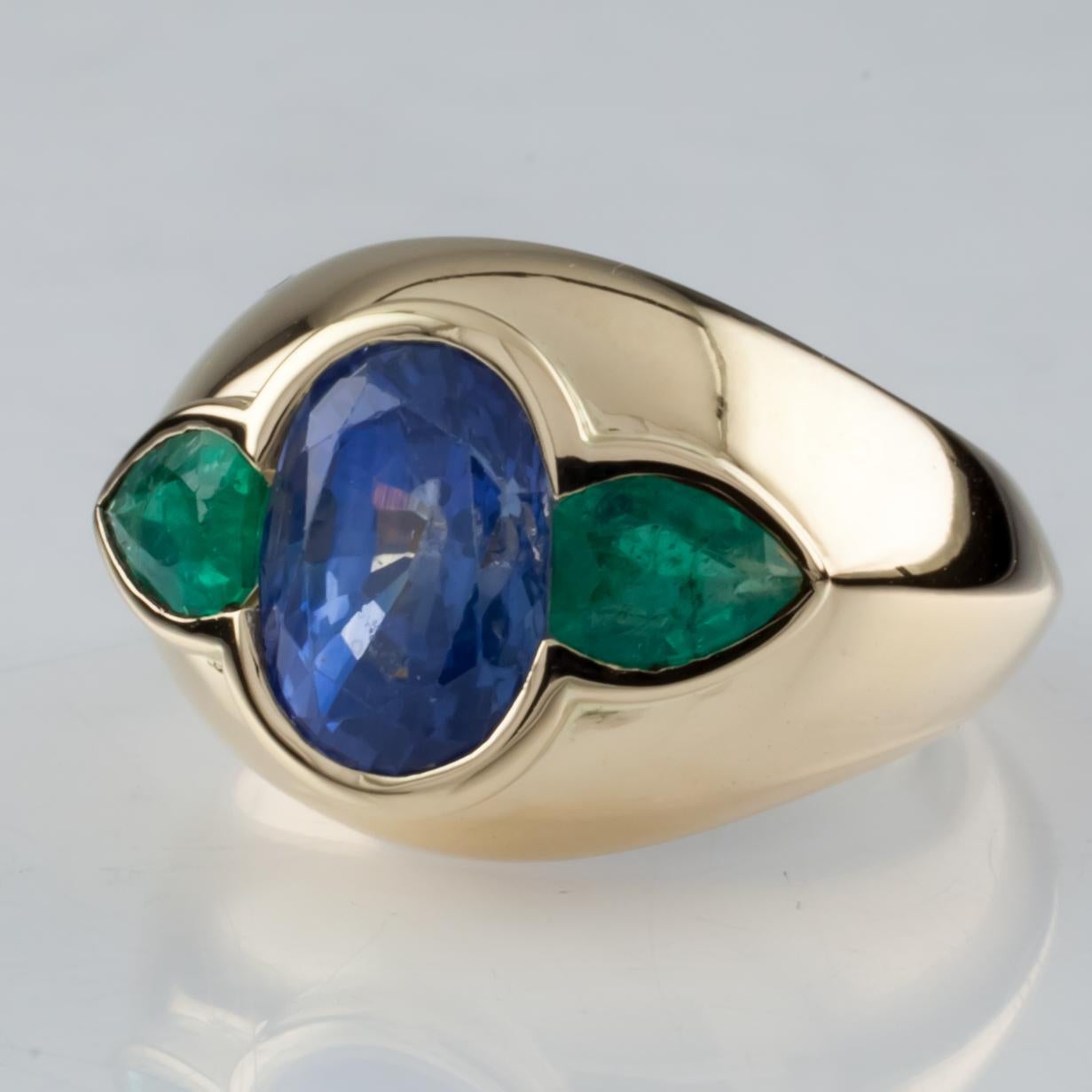 Features Natural Oval Corundum (Sapphire) Center Stone
Color: Transparent Blue
Measurements: 9.50 mm x 7.00 mm x 6.03 mm
Approximately 4 carats
Includes Two Green Modified Pear Mixed Cut Emeralds
Approximately .80 carats
Size: 5
Total Mass = 8.43