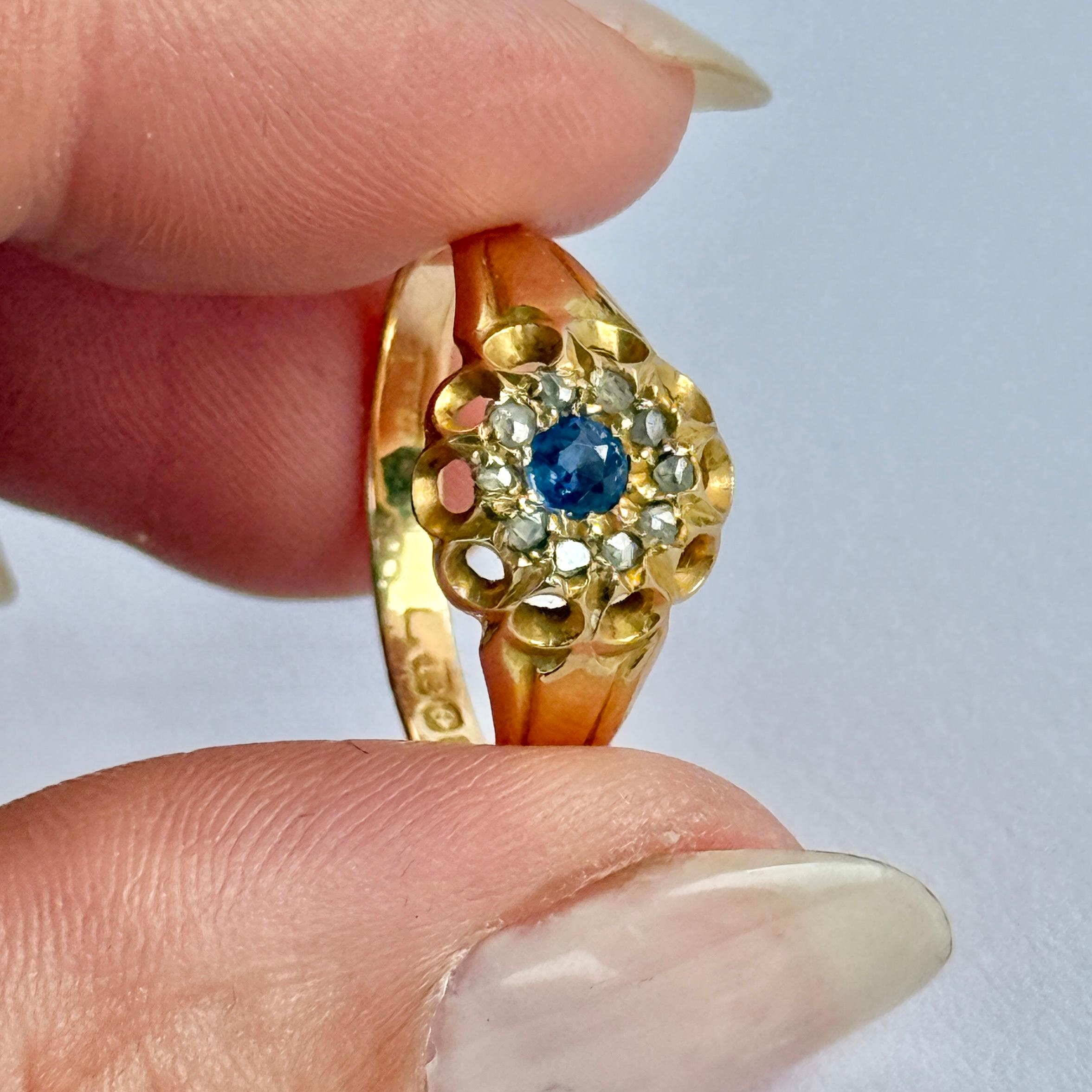 Questo delicato anello a grappolo contiene uno zaffiro al centro di 15 carati, circondato da un'aureola di diamanti di 2 carati ciascuno. La lavorazione del metallo intorno alle pietre contiene un delizioso dettaglio a spirale che si estende fino