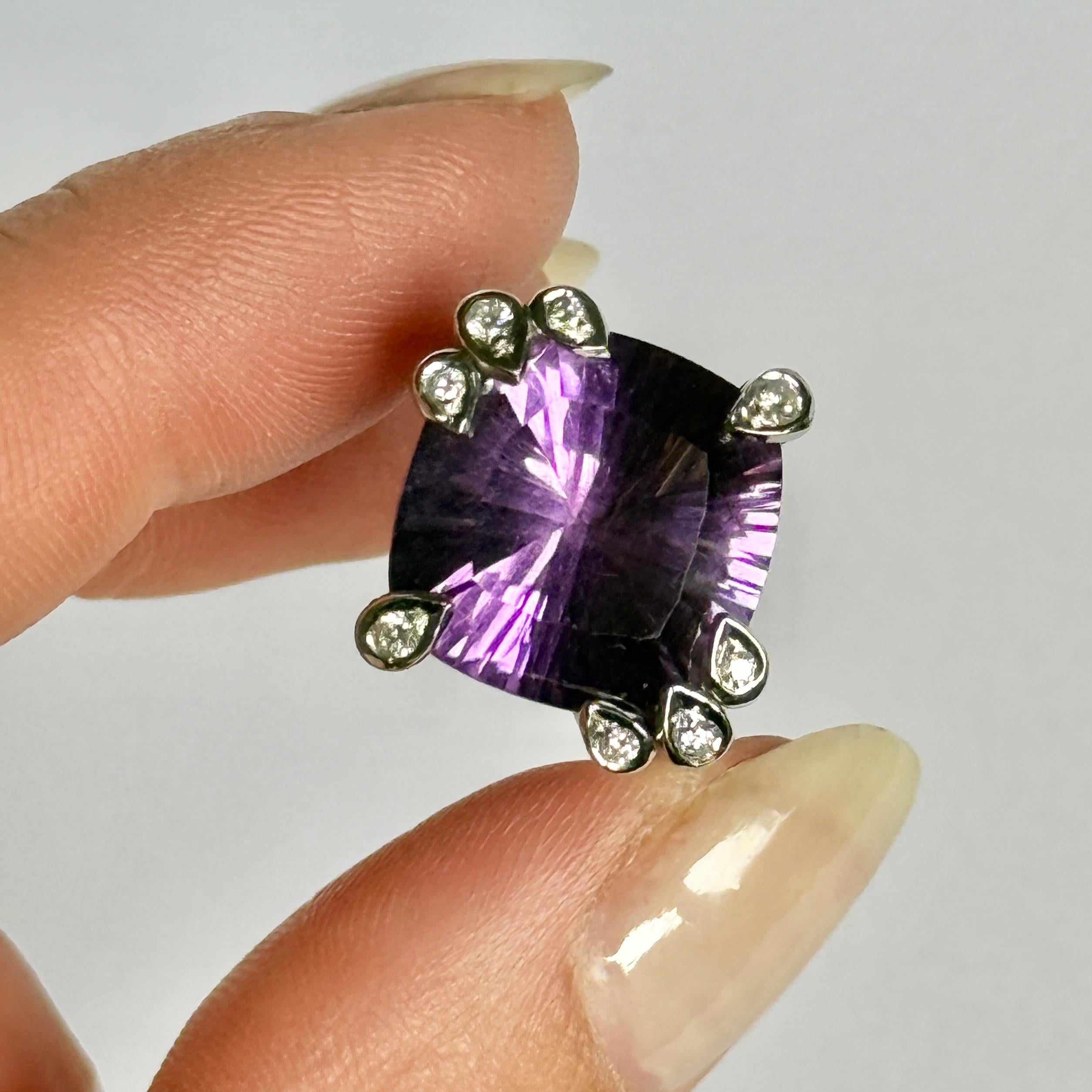 Questo anello ti farà sicuramente notare! Il gioiello racchiude una grande ametista scintillante, con uno splendido effetto a sala di specchi, mentre le chele che trattengono la pietra contengono ciascuna un diamante scintillante! Anche le spalle di