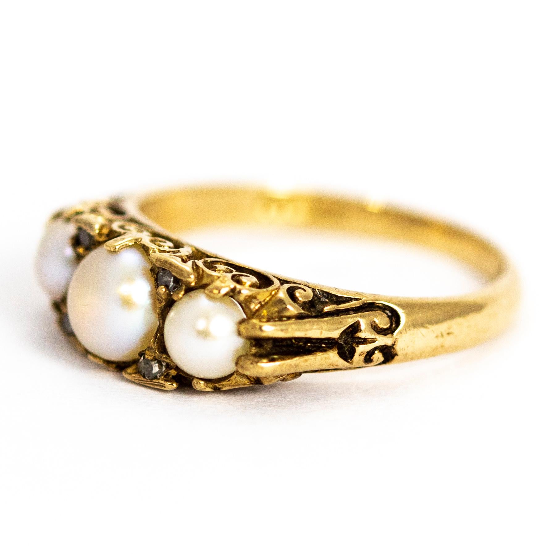 Une merveilleuse bague vintage à trois pierres avec de belles perles graduées et des pointes de diamant entre les deux. Le tout dans une galerie ornée. Modèle en or jaune 9 carats. Entièrement poinçonné en 1979 à Birmingham, Angleterre.

Taille de