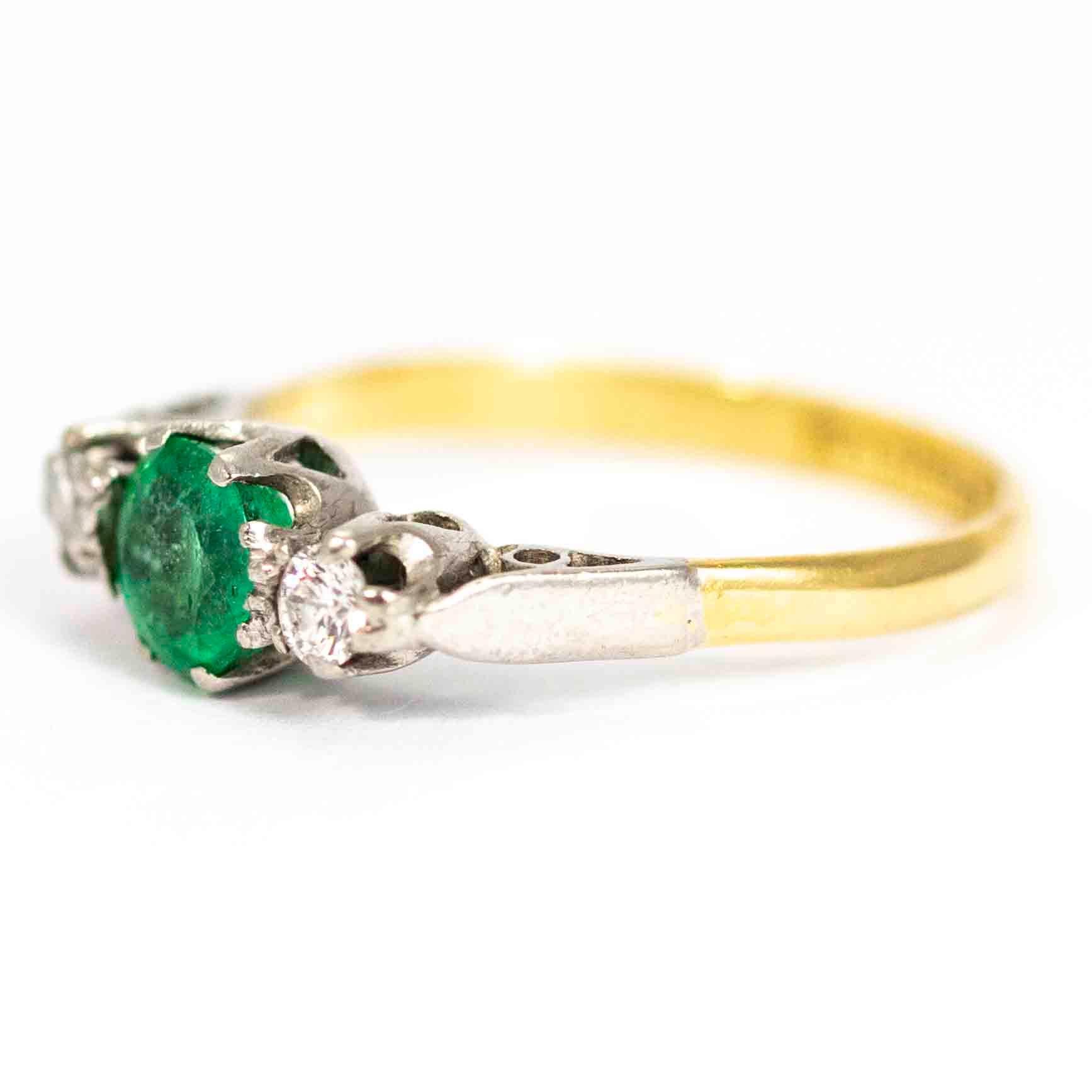 Magnifique bague vintage à trois pierres. Le centre est serti d'une magnifique émeraude ronde mesurant environ 70 points, flanquée de part et d'autre de 10 diamants ronds de taille moyenne. Les pierres et les épaulements sont sertis en platine, le