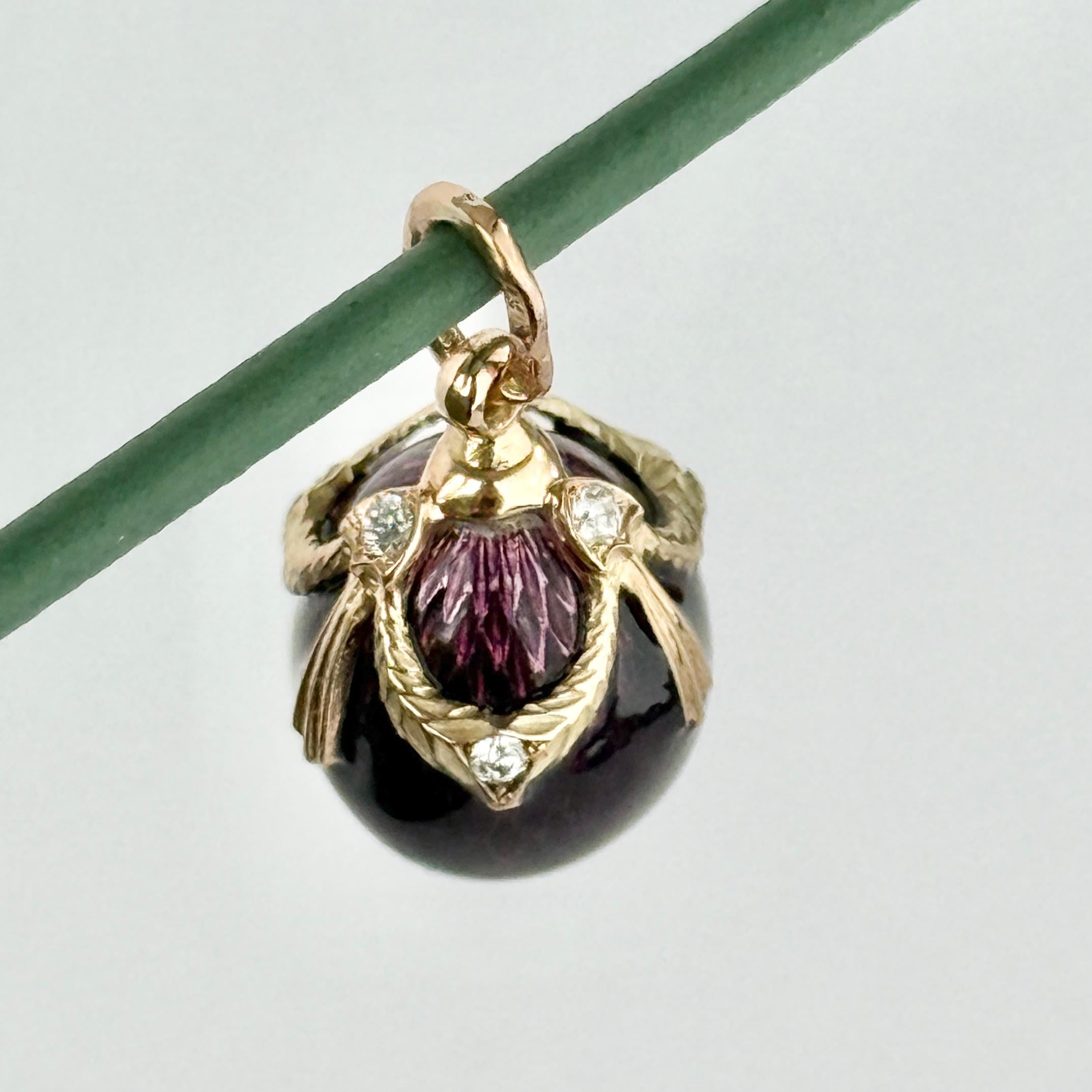 Questo splendido ciondolo è un uovo in oro lucido a 14 carati rivestito di uno splendido smalto viola intenso. L'uovo d'oro è strutturato in modo da conferire allo smalto uno splendido effetto scintillante. Questo uovo contiene anche diamanti