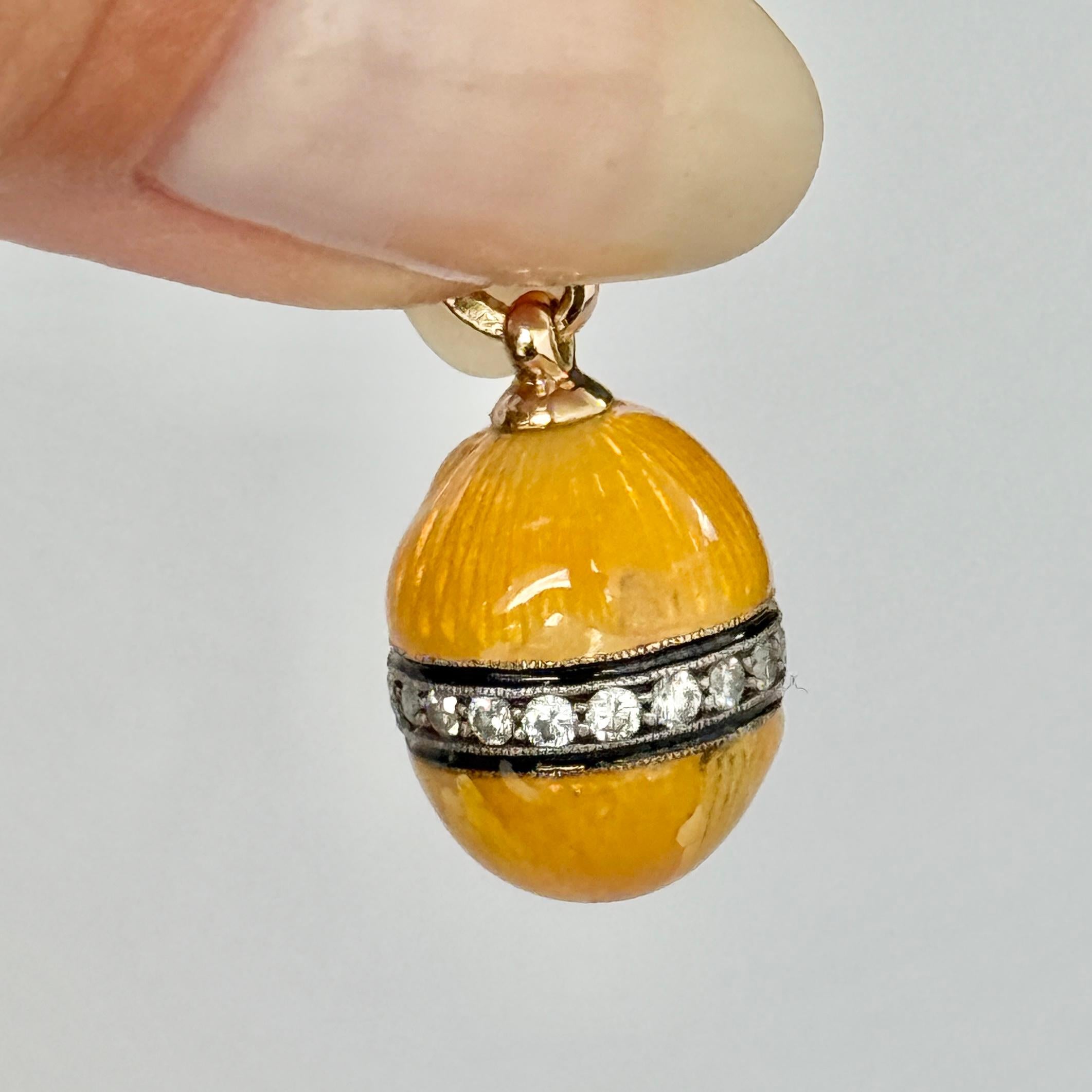 Questo splendido ciondolo è un uovo d'oro lucido a 14 carati rivestito di uno splendido smalto giallo. L'uovo d'oro è strutturato in modo da conferire allo smalto uno splendido effetto scintillante. Questo uovo contiene anche dei diamanti