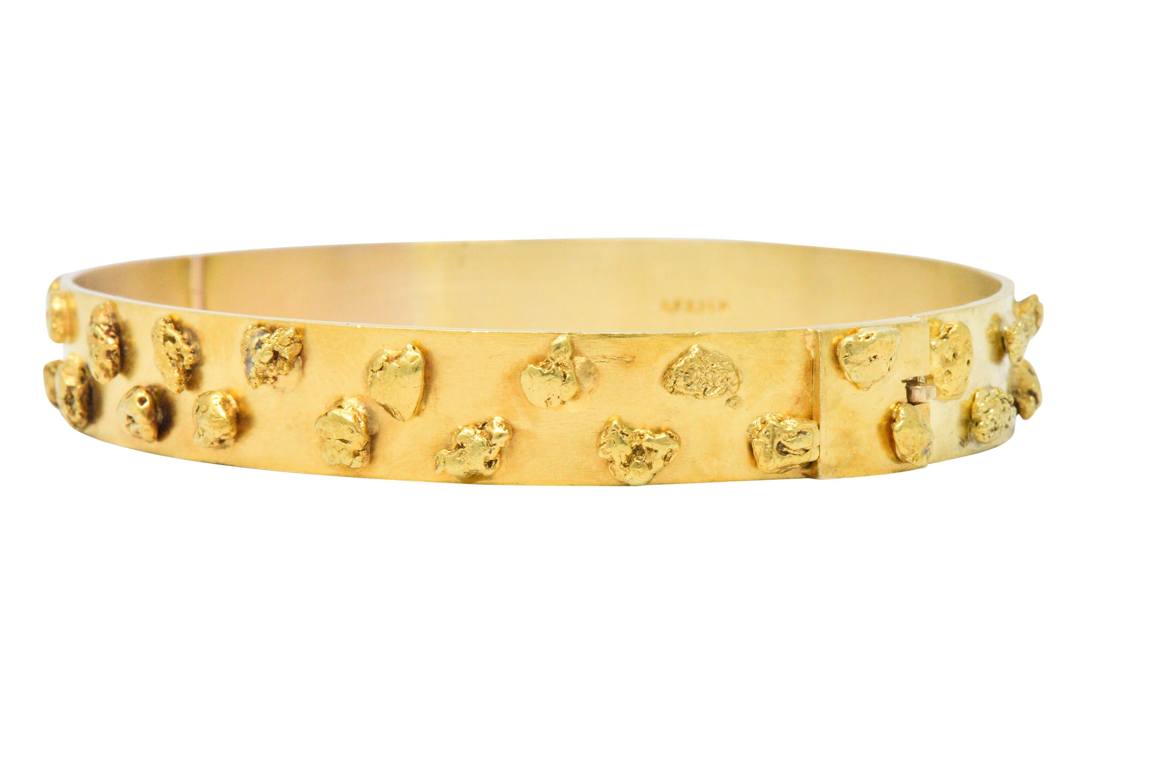 Designed as a flat hinged bangle with applied gold 