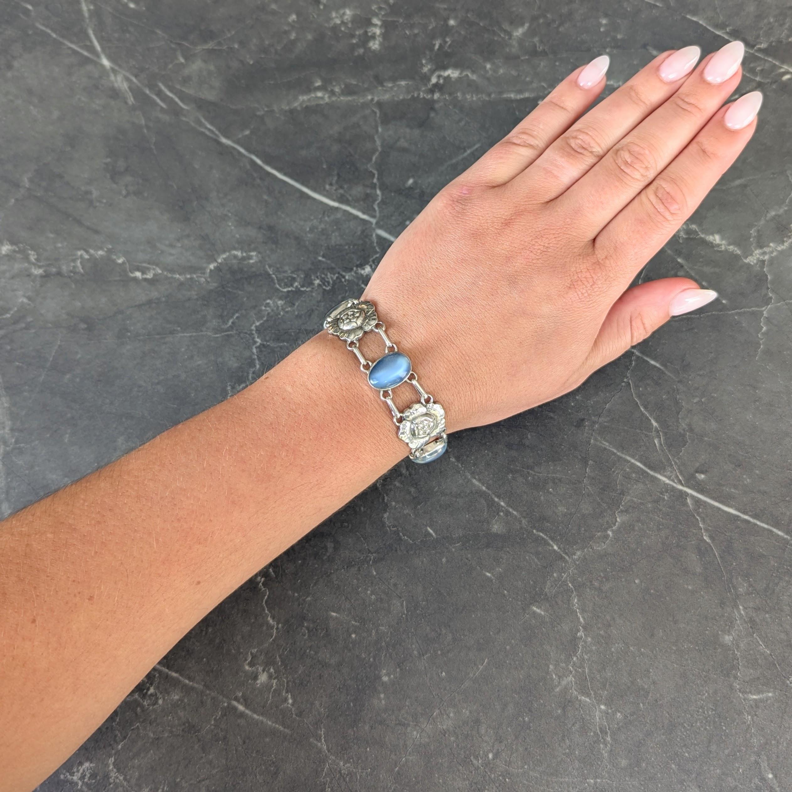 Composto da maglie con motivi floreali scanalati alternati a maglie con cabochon di pietra di luna.
Forma ovale e dimensioni di 10,0 x 15,0 mm - incolore con adularescenza blu vivo
Incastonati in castoni d'argento e con un effetto riflettente