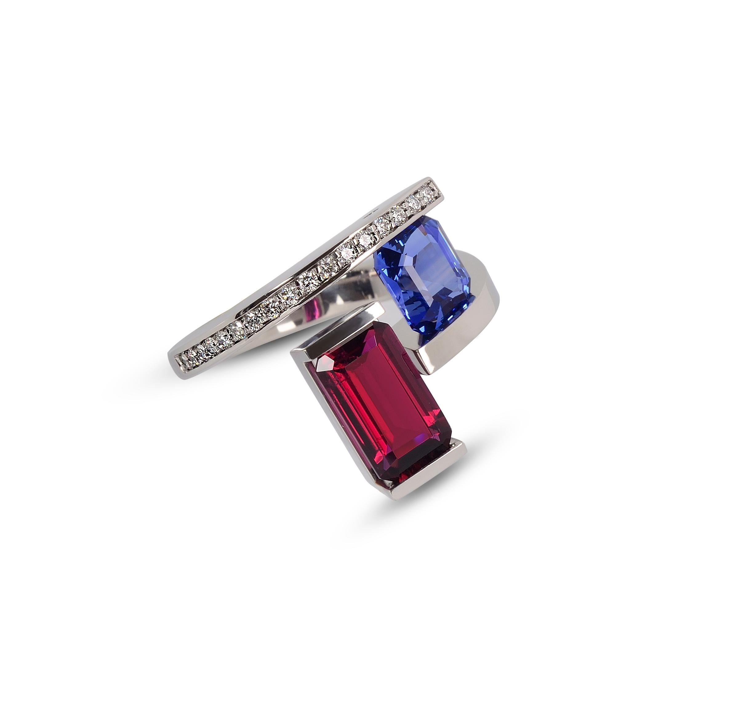The 2-Stone Helix Ring with Rubellite and blue sapphire is handcrafted in platinum with custom 24k crystalized gold inlay accents. The ring features a 3.44 ct. burgundy rubellite and a tension-set 2.44 ct. medium cornflower blue sapphire. The top of
