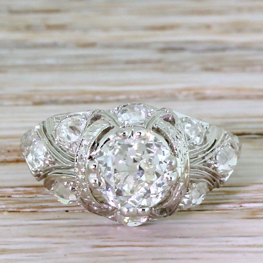 An elegant and ornate Edwardian diamond engagement ring. The HRD graded old mine cut diamond in the centre is secured by four split claws, and sits atop a wonderfully ornate and refined setting. Eight chunky old mine cut diamonds are set in the