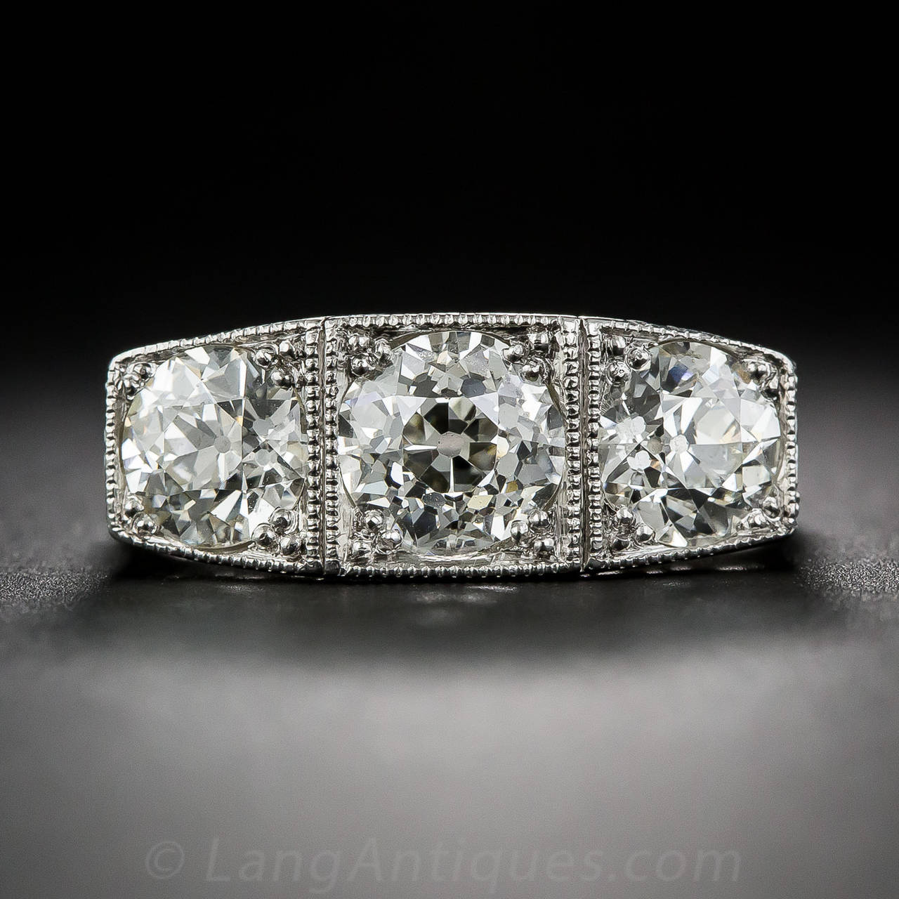 A dazzling Art Deco three-stone ring, crisply die-struck and hand detailed in platinum - circa 1925. This consummate Jazz Age jewel features a seductively sparkling trio of old European-cut diamonds which curve across your finger in a continuous