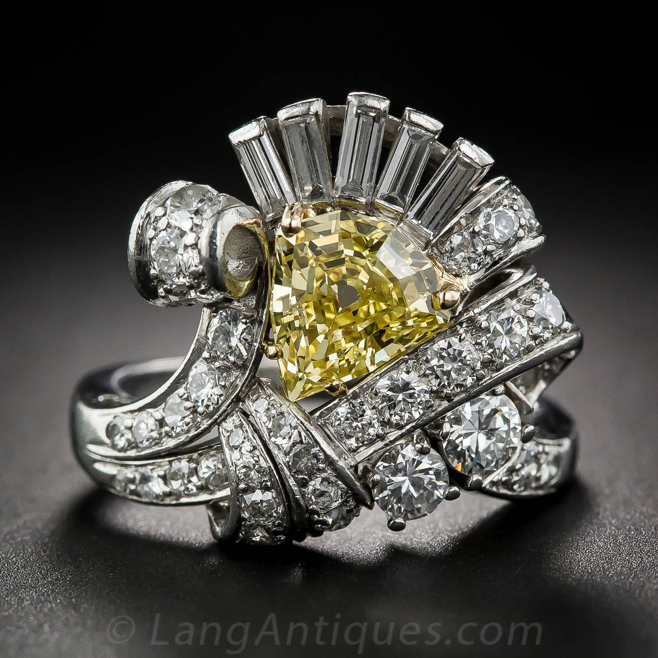 A truly singular and sensational late-Art Deco ring featuring an equally unique and stunning center stone. A fancy, canary yellow, step-cut shield shape diamond, weighing 1.53 carats and bearing a GIA Colored Diamond Grading Report stating: Natural