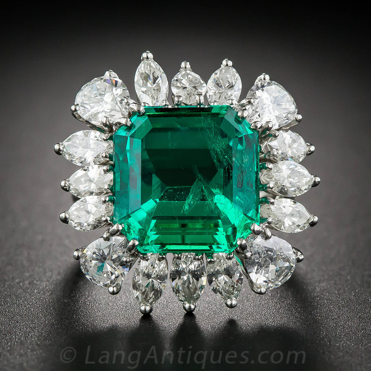 A big, bold and beautiful, square emerald-cut Colombian Emerald, with a bright, richly saturated, luscious, crystalline green color - weighing 9.06 carats - radiates from within a sparkling platinum and diamond frame composed of bright-white