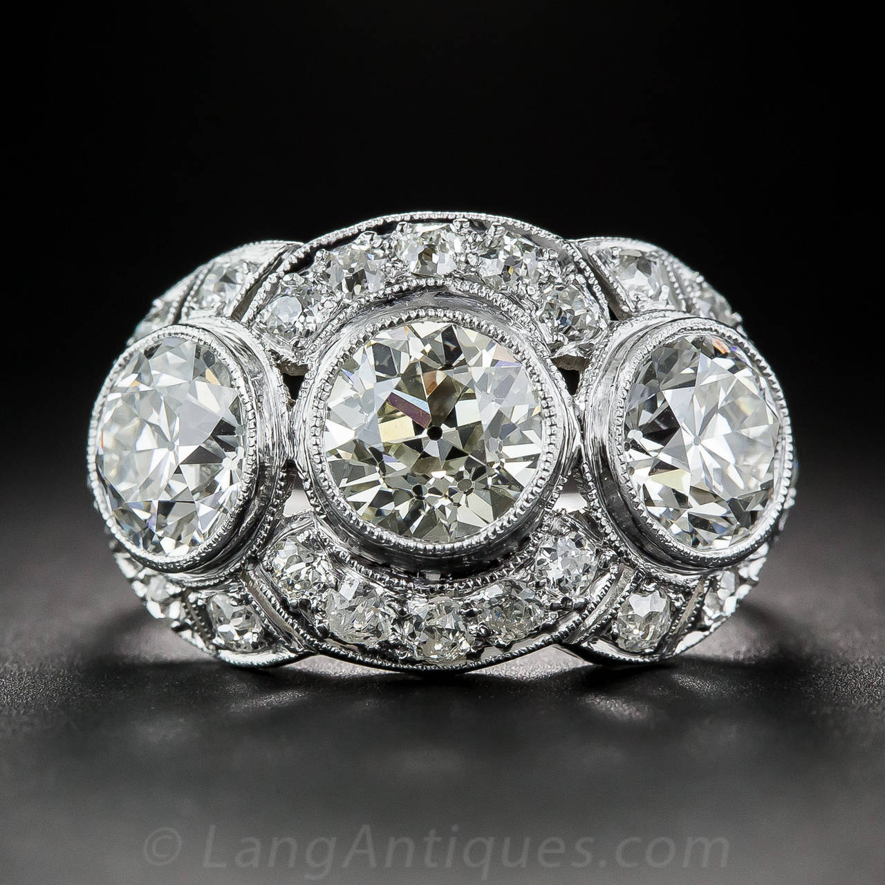 This spectacular 'wow!' ring wraps your finger with three bright-white and blazing European-cut diamonds totaling 3.65 carats. The tantalizing trio radiate from within slightly raised bezel settings, each of which is embraced by a partial circle of