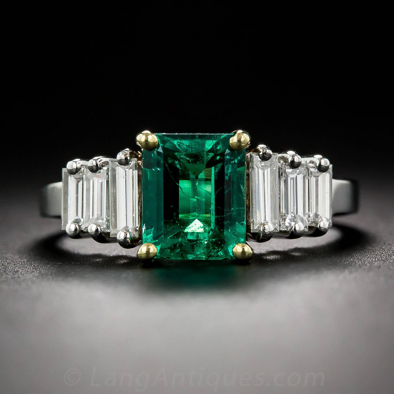 Bright icy-white diamond baguette steps lead up to a luscious, richly saturated, crystalline emerald, weighing 1.50 carats, with a vibrant green color that would be difficult to improve upon. The 'gemmy' gemstone is set in 18K yellow gold and the