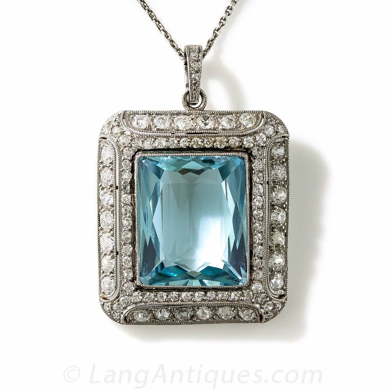 This thoroughly enchanting original Art Deco jewel, circa 1920s, highlights a placid, pastel blue Aquamarine, weighing 10 carats. The rectangular gemstone is artfully fashioned with striking scissor-cut faceting and fills an stunning, decoratively