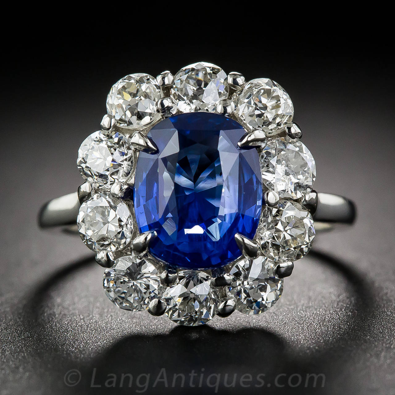 From early twentieth-century France comes this classic halo ring featuring a gorgeous, natural, no-heat sapphire, weighing 3.51 carats. The faceted, velvety royal-blue gemstone radiates from within a sparkling halo of bright, high-color old mine-cut