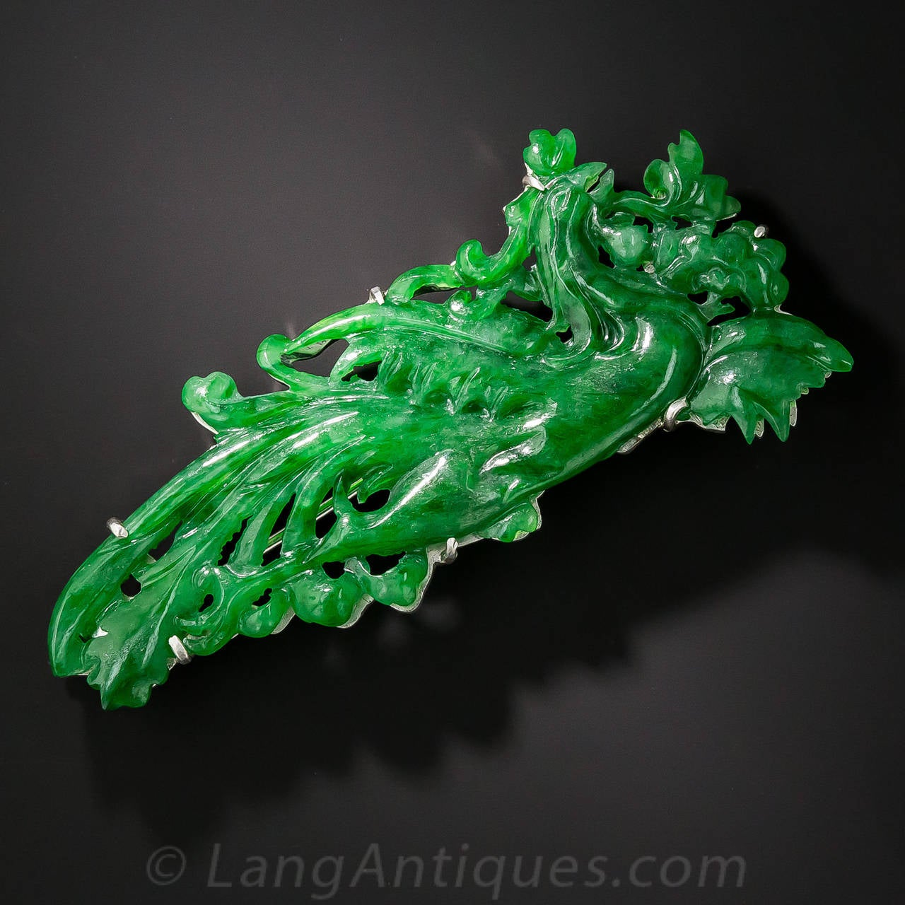 This very verdant and fanciful fowl, with flowing, rich translucent green plumage, is artfully carved in natural Burmese jade and measures an impressive 2 and 1/2 inch long by 1 and 1/8 inch high. The colorful brooch is backed in silver with a white