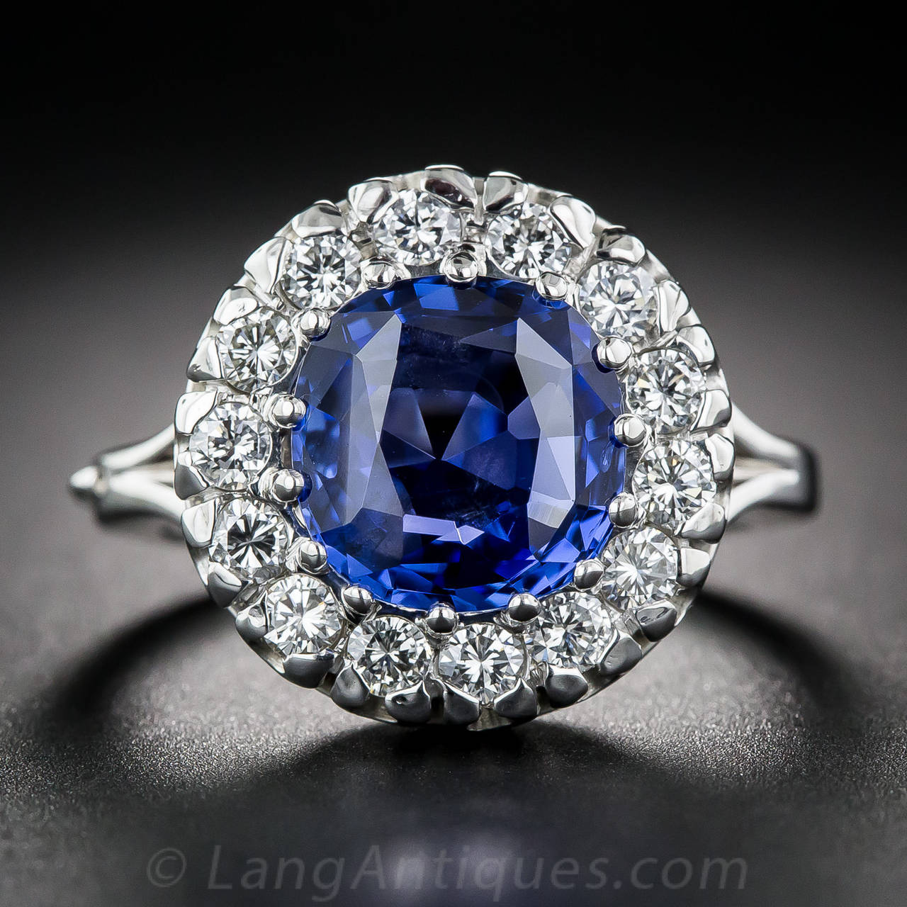 A fine blue, untreated sapphire is elegantly surrounded with a frame of sparkling white diamonds in this classic 'Lady Di' style ring, crafted in bright 14K white gold - circa mid-twentieth century. The velvety sapphire is quite extraordinary