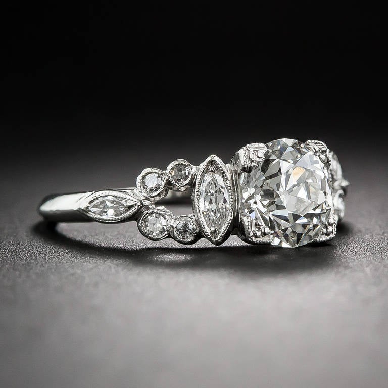 The distinctive design of this 1920s vintage engagement ring defies easy categorization. The symmetry and vintage places it into the early-Art Deco style period, however, the fanciful shoulders, composed of collet-set navette and round diamonds,