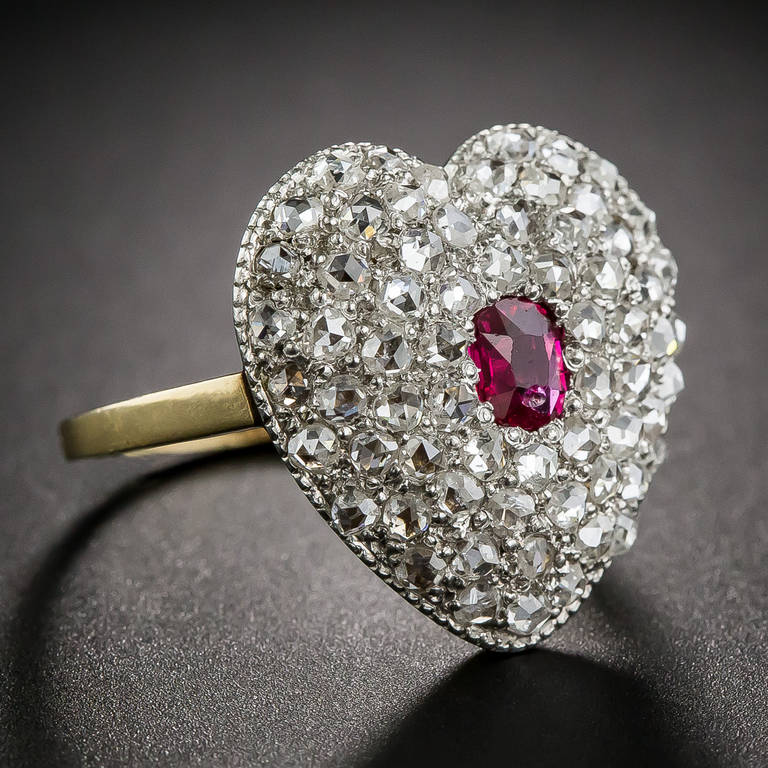 This romantic and ravishing heart shaped ruby and diamond ring, dating from the turn-of-the-last-century, is tightly paved with fine, bright-white, high-domed rose-cut diamonds of a quality we rarely see. The gently puffed heart is crafted in