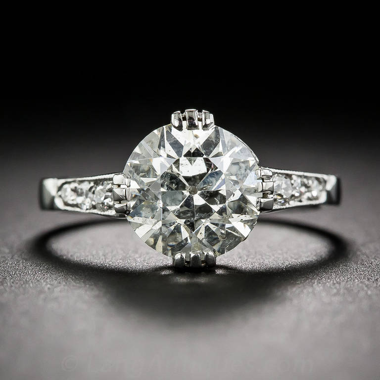 This spendid and splashy original vintage engagement ring, dating from the early-twentieth century, sparkles front and center with a bright and shining European-cut diamond weighing two-and-a-half-carats. The scintillating stone resides in a a