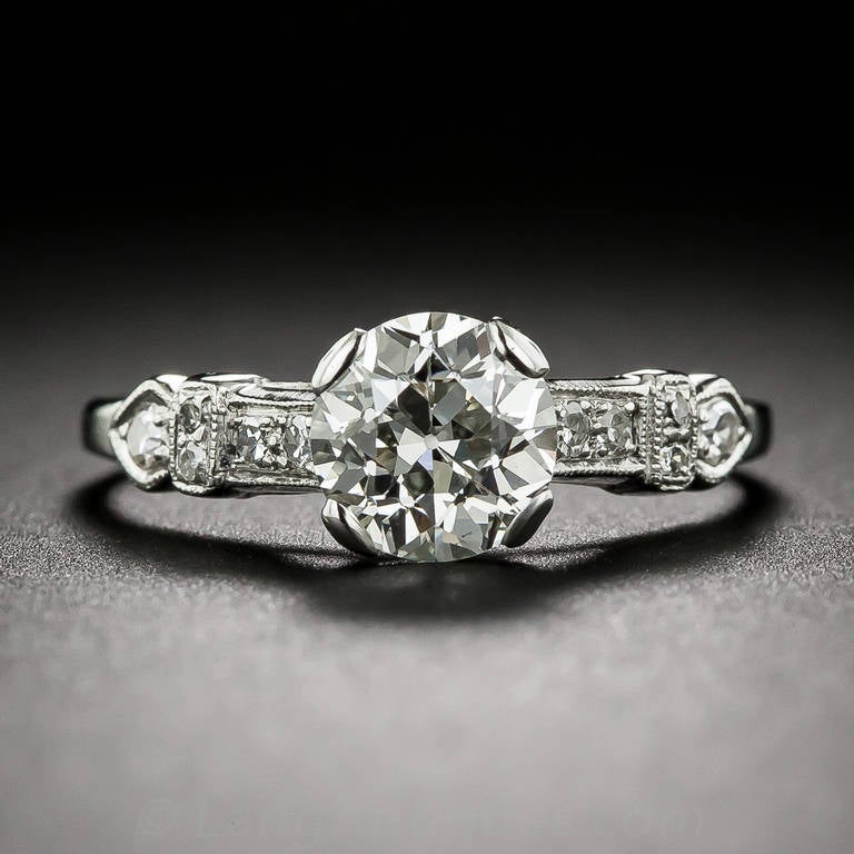 A traditional platinum and diamond engagement ring but with a stylish and sophisticated Art Deco twist. A gorgeous ultra-sparkling European-cut diamond, weighing 1.12 carats, is supported by sharply angled shoulders designed with sleek diamond-set