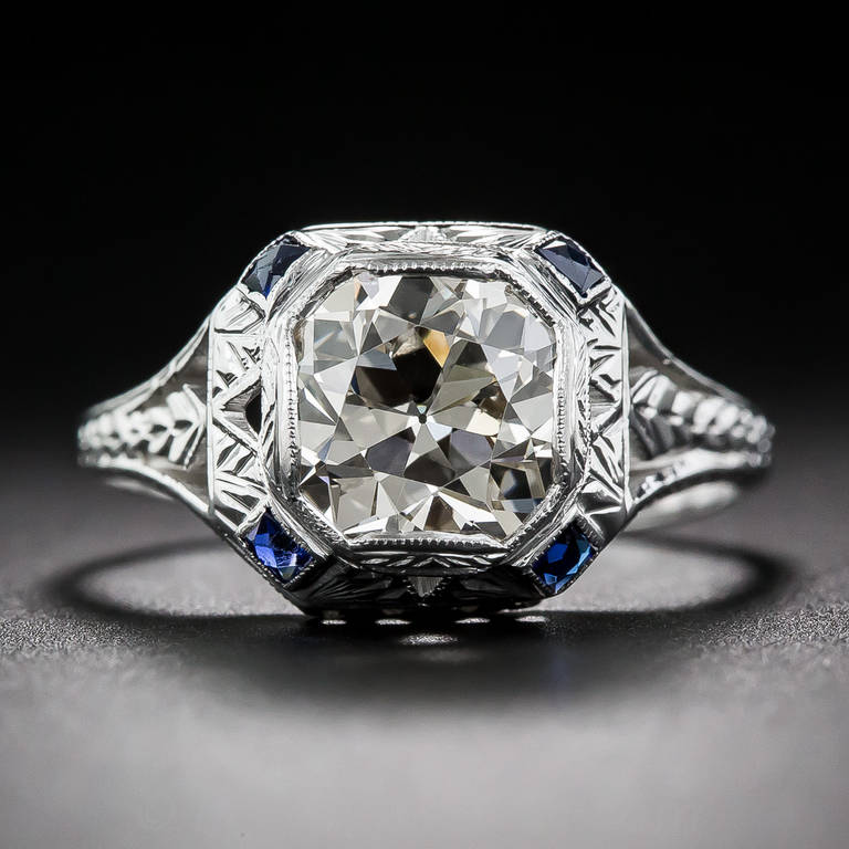 A gorgeous and glistening European-cut diamond, weighing 2.10 carats, takes on a geometric look thanks to its artfully fashioned octagonal setting. The steeply beveled top is cornered by four royal blue scissor-cut synthetic sapphires (original to