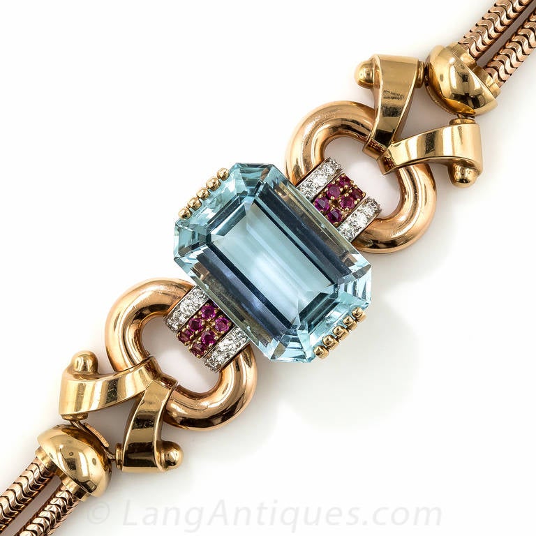 This strikingly stunning rose gold Retro bracelet by Tiffany & Co. presents a gorgeous, sizable (46.00 carat) and beautifully modeled emerald-cut aquamarine with a rich, even sky blue color. The enchanting gemstone glistens between a pair of ruby