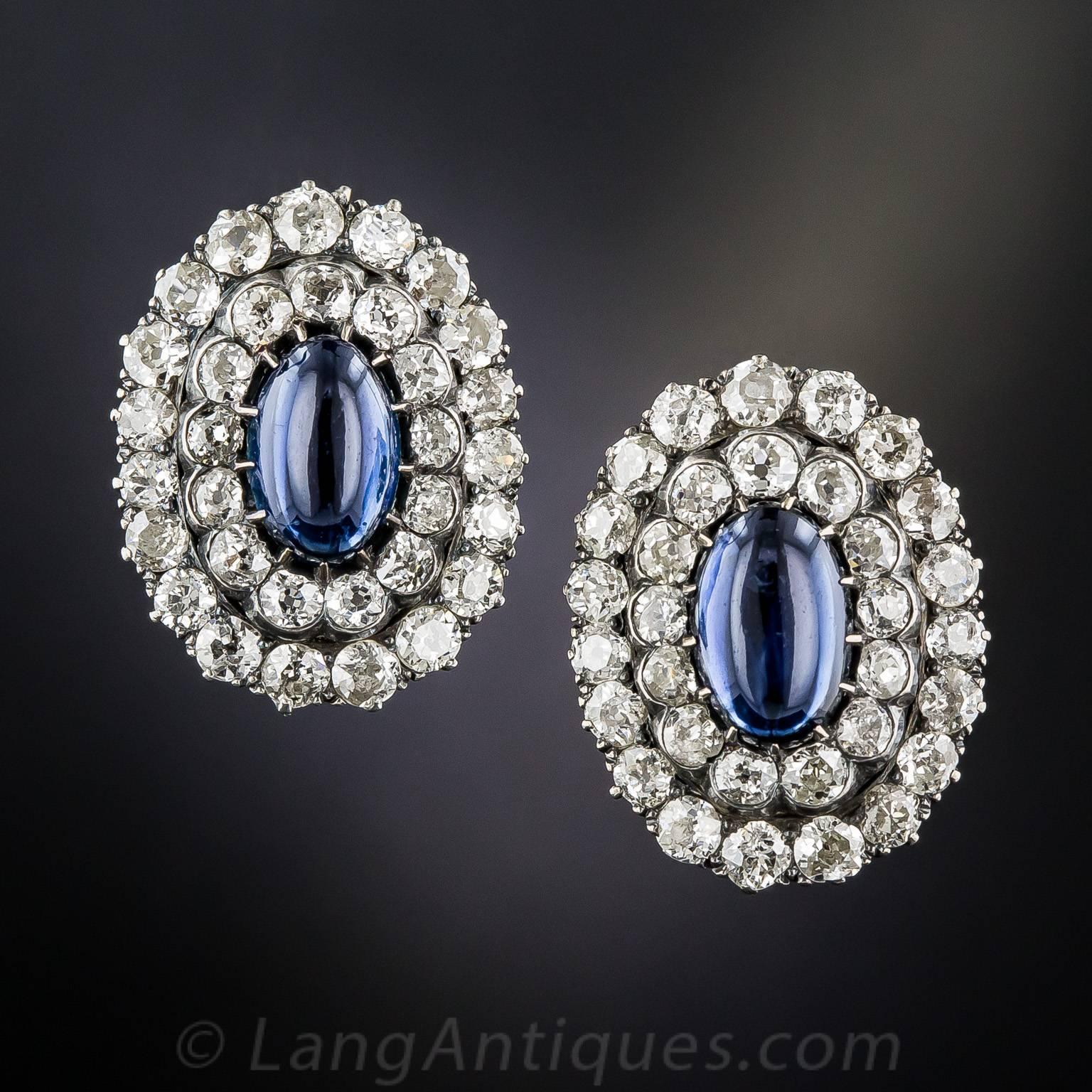 Dating from the late-19th century, these enchanting one-inch-long cabochon sapphire and diamond earclips glisten with concentric ovals of bright white diamond sparklers, totaling 6.00 carats. The elongated oval cabochon sapphire centers, together