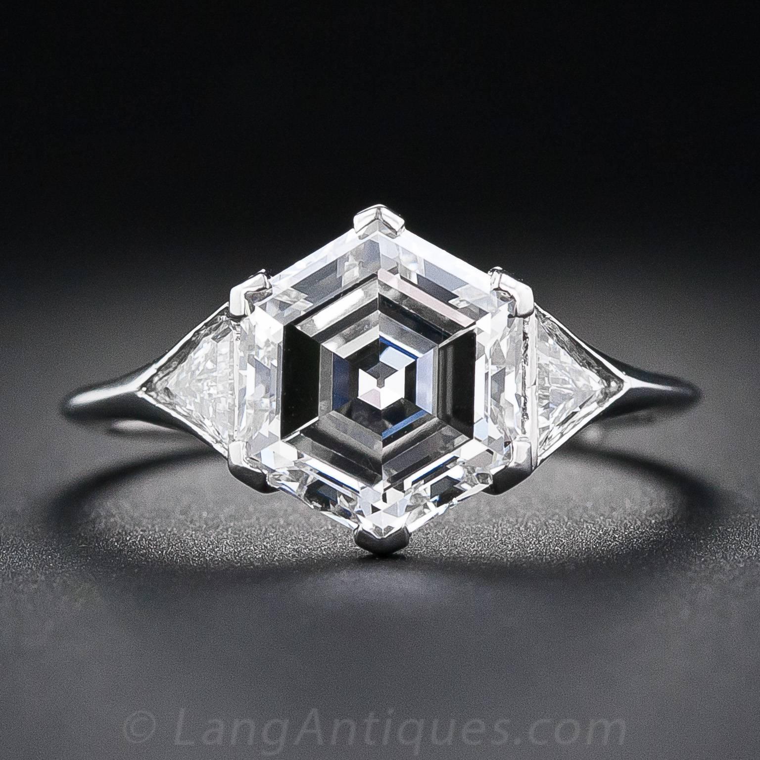 A uniquely beautiful Art Deco diamond engagement ring featuring an entrancing and enchanting hexagonal-cut diamond weighing just nine points shy of three carats. This rare and radiant rock is set with chevron-shape prongs between a sparkling pair of