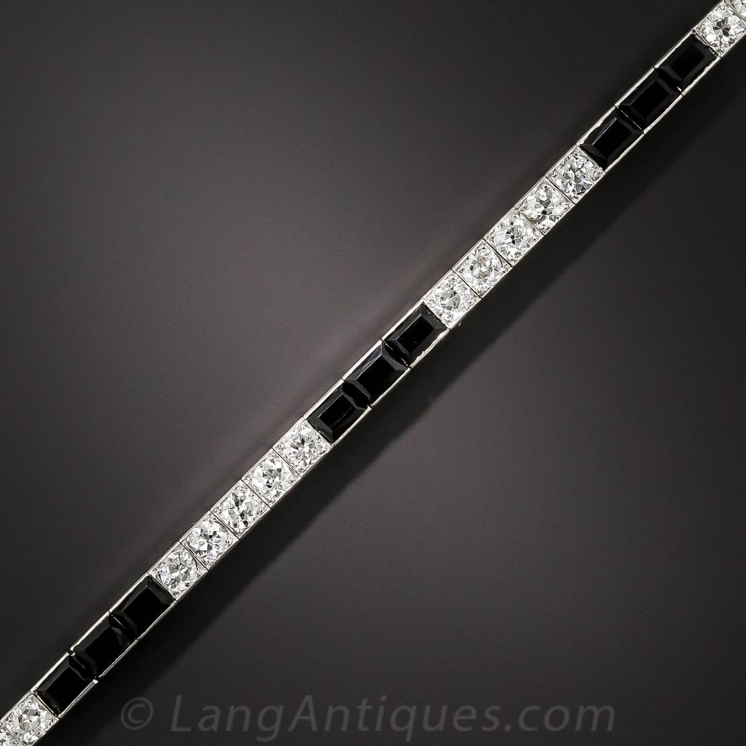 Hand-fabricated in platinum, in glorious black & white, during the peak of the Art Deco design period - circa 1925 - comes this sleek and sophisticated classic from Cartier. Sections of four bright, white European-cut diamond sparklers, totaling