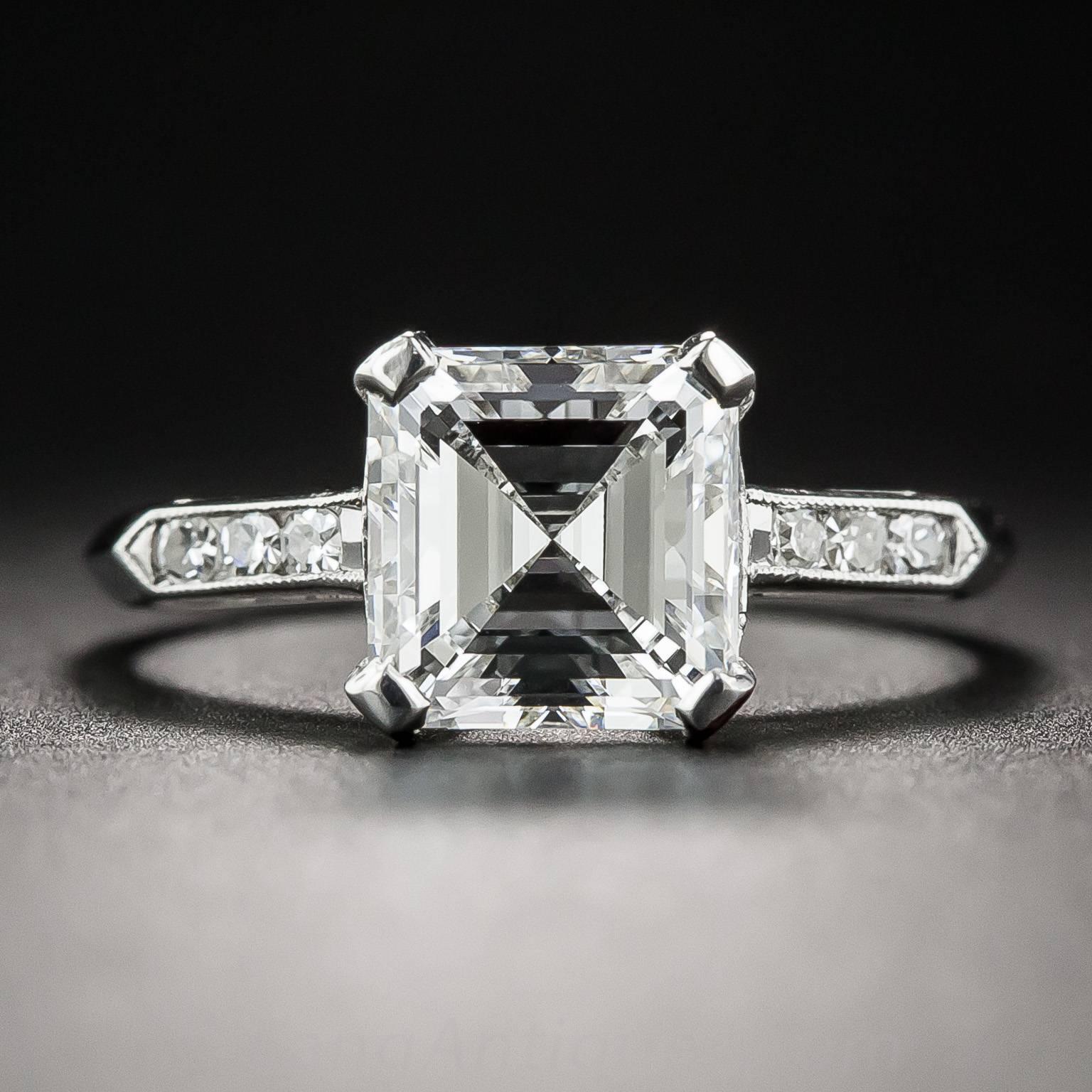A bright icy-white and square emerald-cut (aka Asscher-cut) diamond, accompanied by a GIA Diamond Grading Report stating: F color - VS1 clarity, radiates from within a sleekly tailored hand-fabricated platinum mounting, modestly embellished with