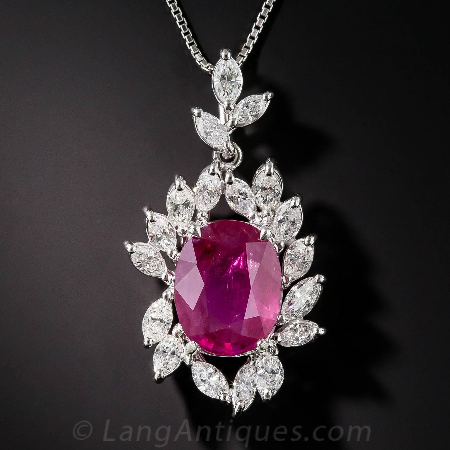 Stunning! A beautiful bright and vibrant faceted oval Burmese ruby, weighing in at an impressive (and lucky) 7.71 carats. The magnificent gemstone glistens and glows from within a sparkling frame composed of bright white marquise diamonds, totaling