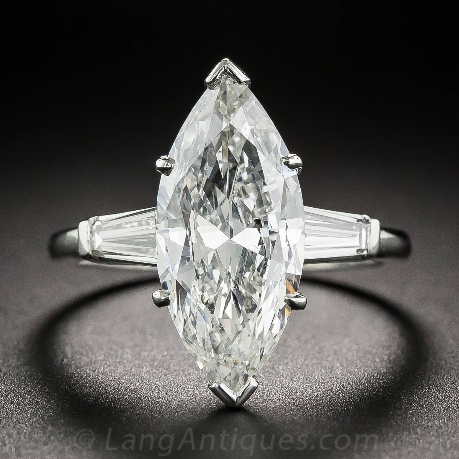 A stunning, sleekly modeled marquise-cut diamond, weighing 3.71 carats, is classically presented in a hand-fabricated platinum ring between a pair of bright tapered baguette diamonds, together weighing .50 carat. The sparkling white, elegantly