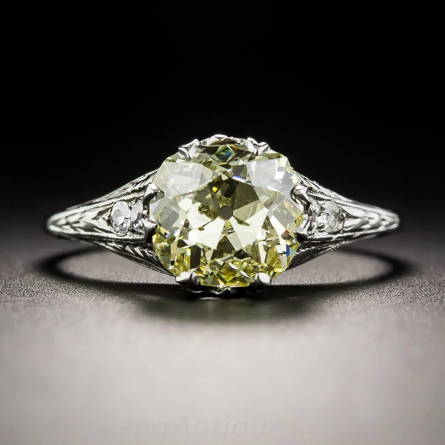 A beautiful bright sunshiny yellow antique cushion-cut diamond, weighing 2.02 carats (graded Fancy Intense Yellow - VS2 Clarity by the GIA) radiates from atop a refined, neoclassically inspired original Art Deco mounting, die-struck and