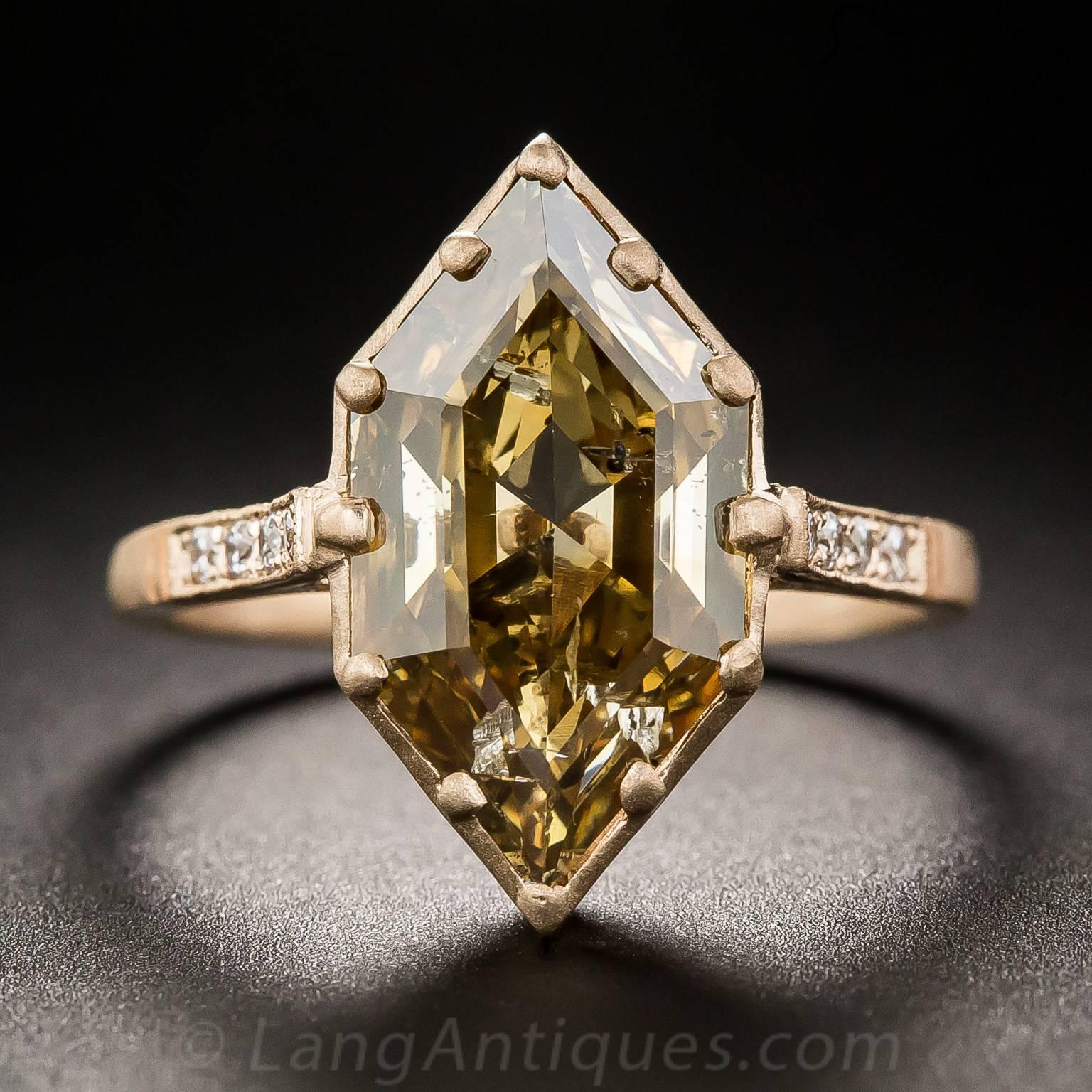 This uniquely striking and impressive dazzler features a rare and wonderful elongated hexagonal-cut diamond, weighing 3.43 carats, suffused with a fascinating cognac colored glow. Measuring 5/8 inch long, the diamond radiates with minimal