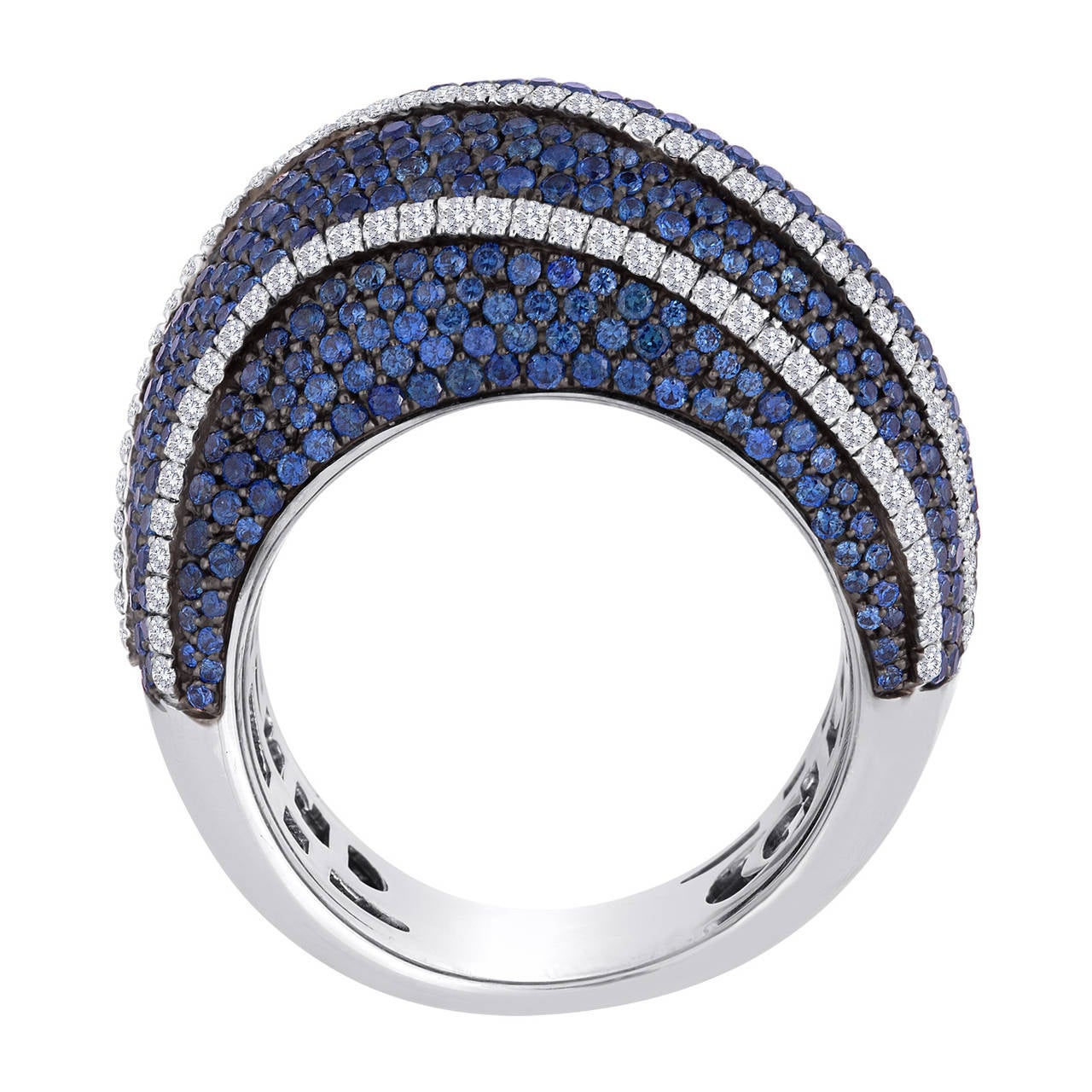 This piece consists of multiple rows of blue sapphires and white diamonds, arranged in an elegant wave-like pattern. The total weight of the diamonds is 1.25 cts. The total weight of the sapphires is 1.68 cts. All stones are pave set in 18k white